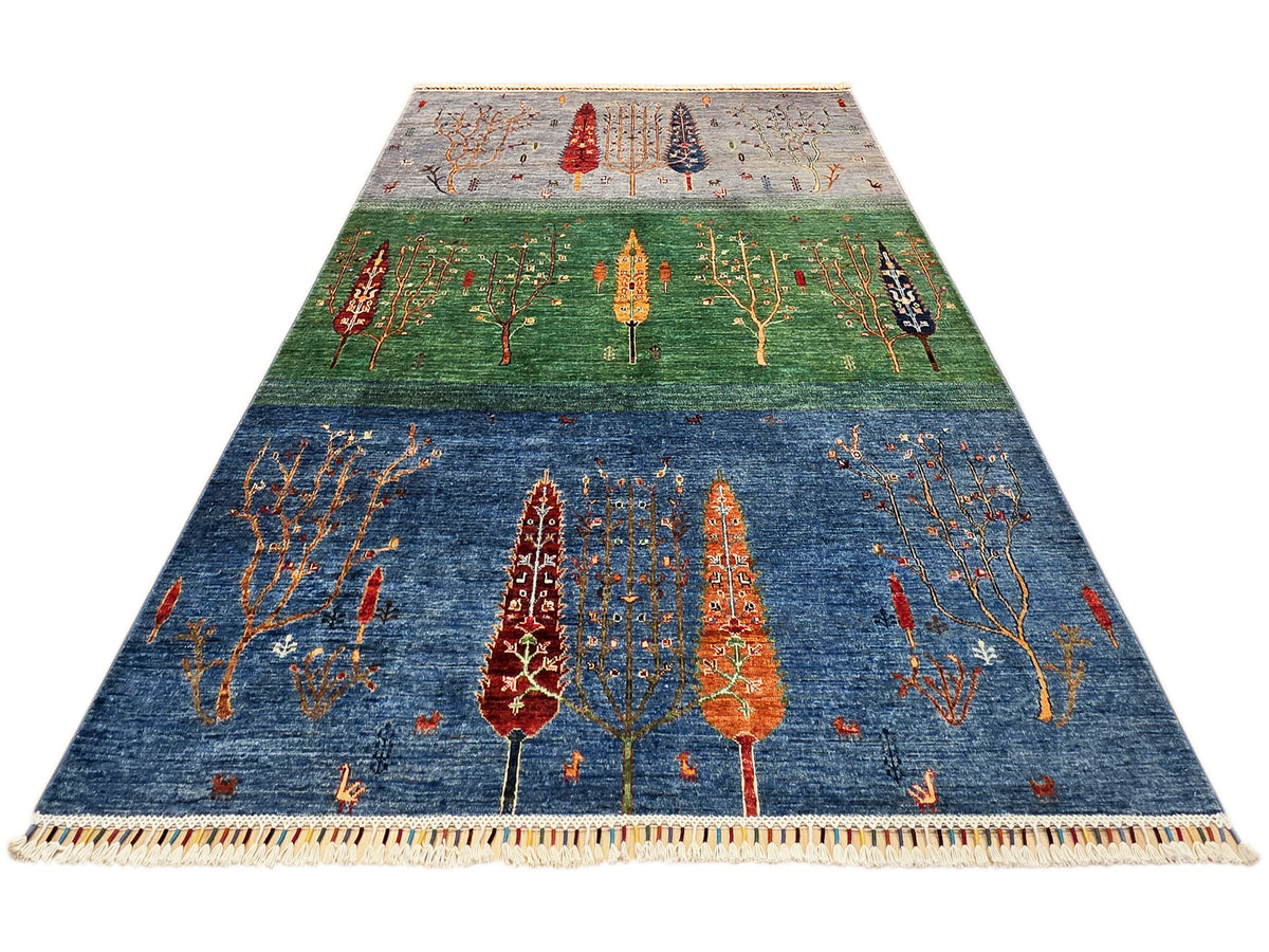 Blue and green area rug with orange tree motifs and beige fringed border.