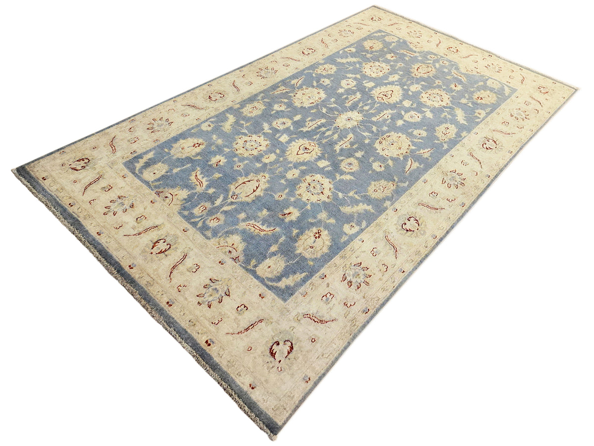 Afghan rug angled view with cream border and blue field with repeating flower patterns