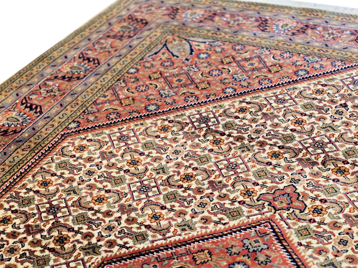 Bidjar rug close-up with ornate red, blue, and cream patterning.