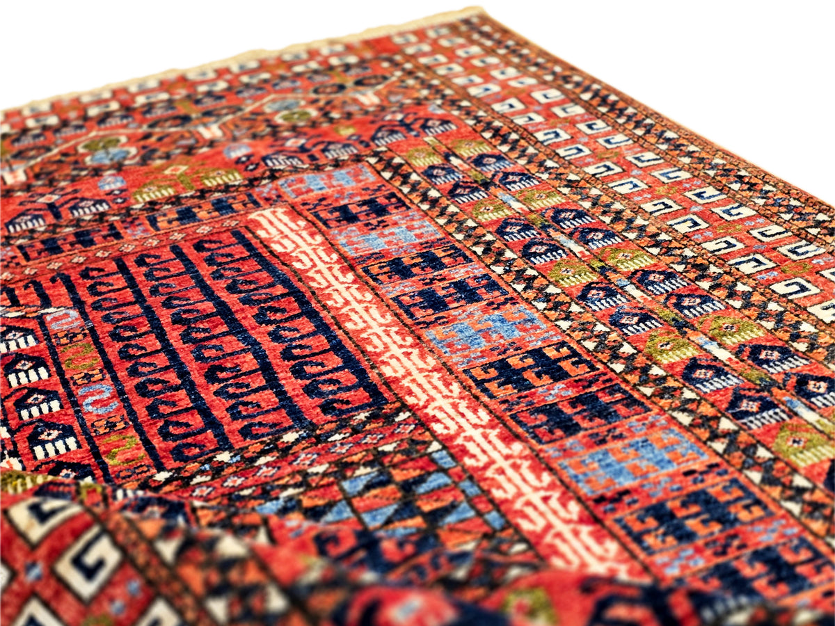 Close-up view of rug pattern with red, blue, and beige block motifs and woven texture