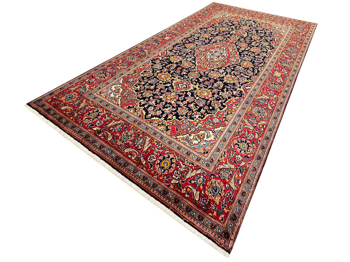 Red and navy Persian-style rug with cream outer edge and central floral medallion design.