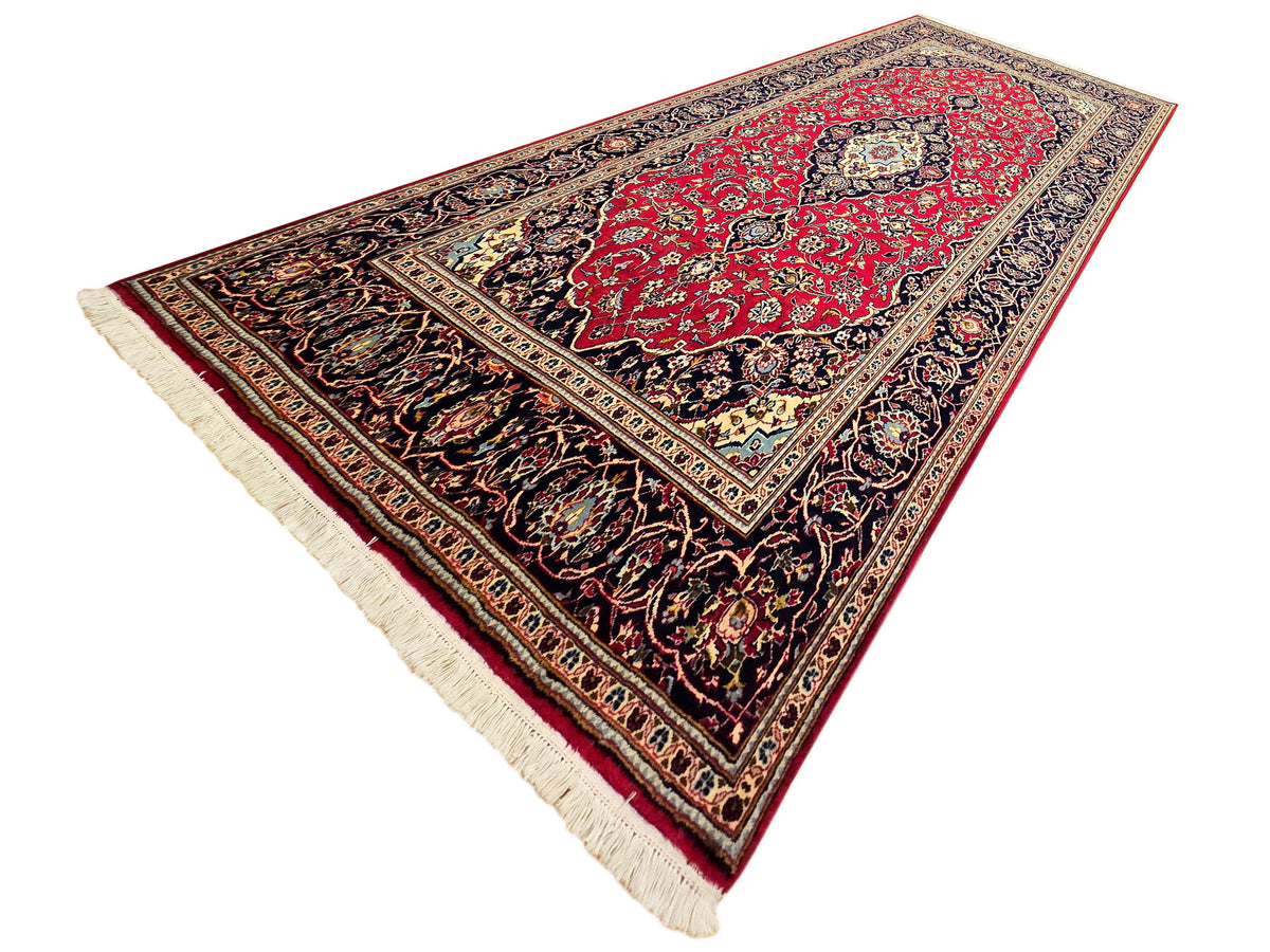 Kashan rug triangle view, red centerpiece with dark floral scrolls and cream fringe