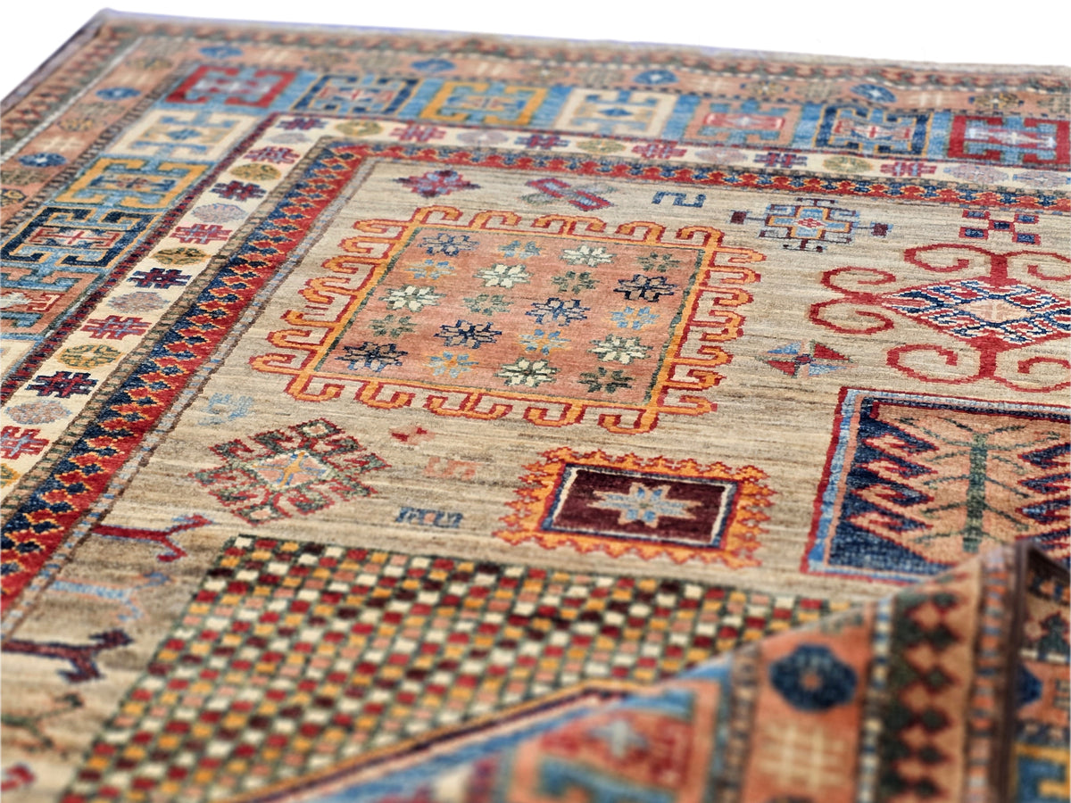 Kazak-style rug texture close-up with orange center panel and blue corner motifs on light base
