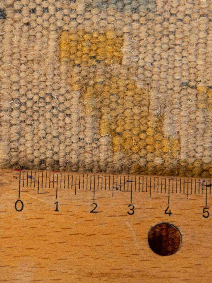 Kilim rug close-up of textured loop pile in beige with small yellow diamond accents