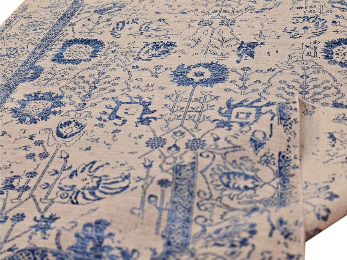 Close-up of blue floral and arabesque motifs on cream rug surface