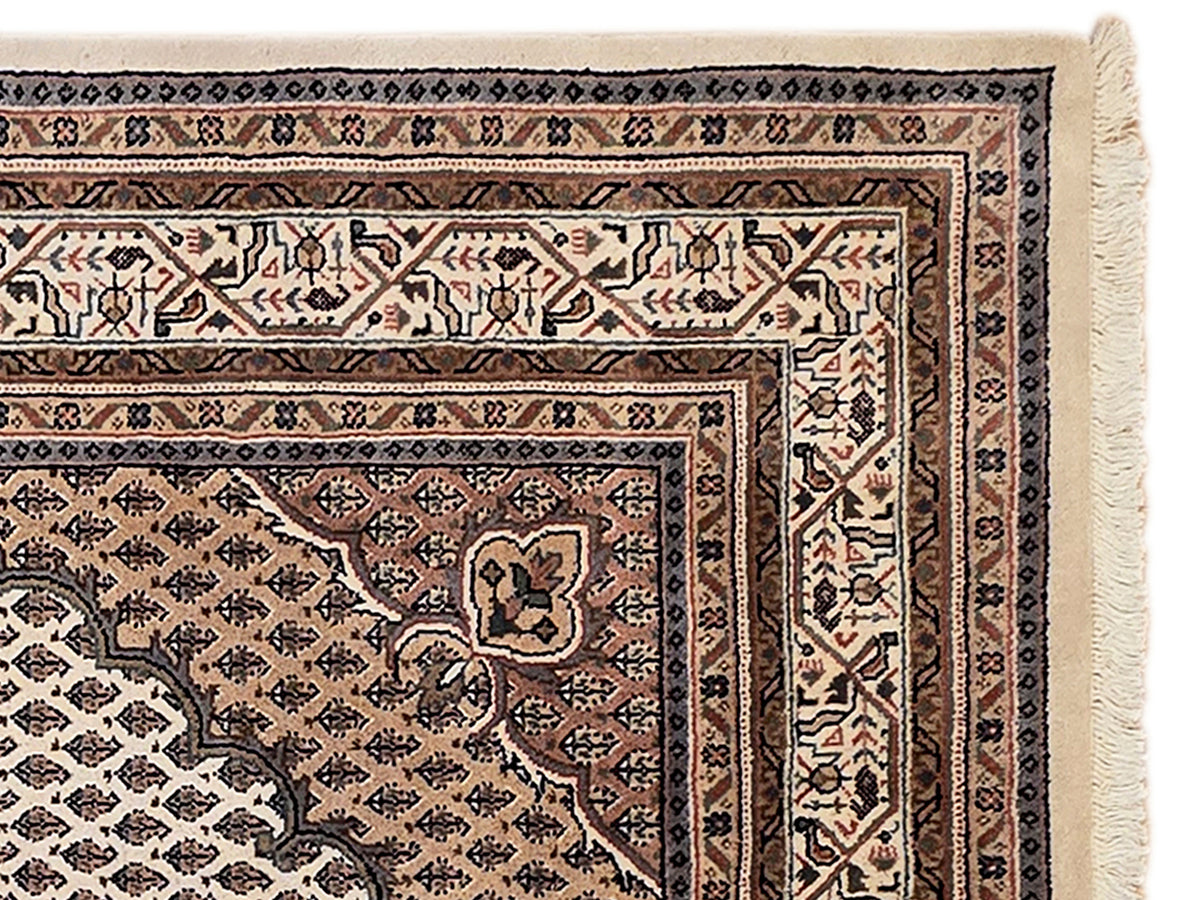 Close-up of rug border with geometric motifs in dark brown, tan, and ivory tones