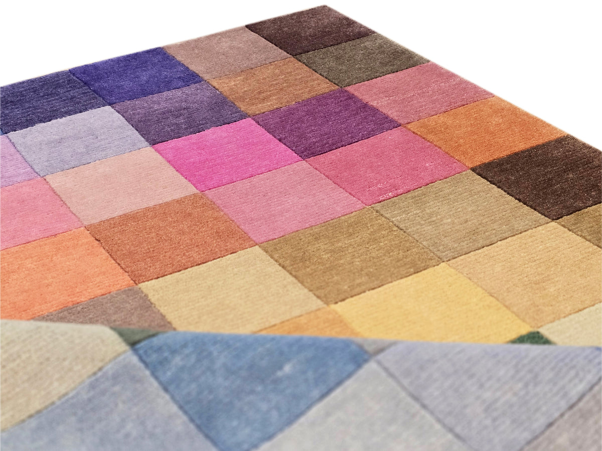 Multicolor patchwork rug with angled square blocks in pink, orange, purple, and blue
