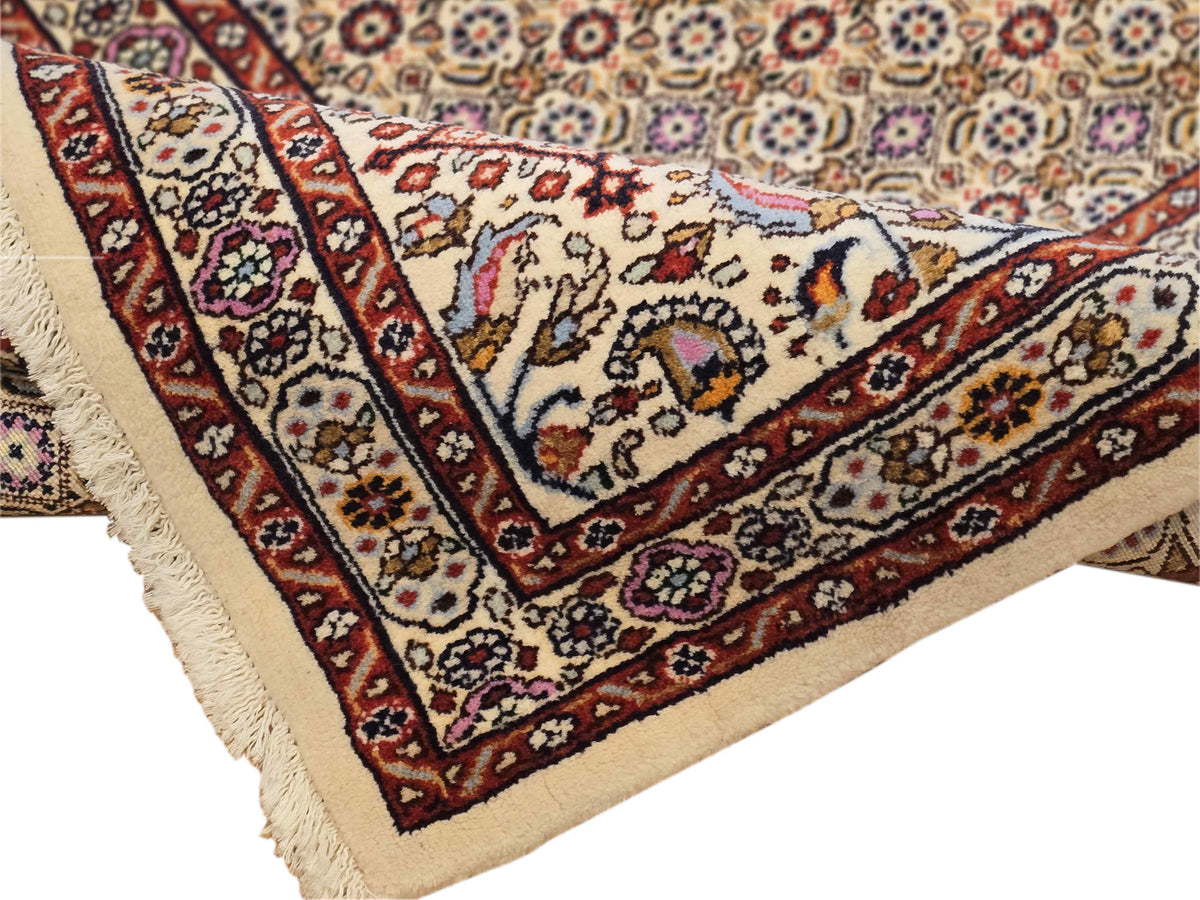 Persian rug corner with detailed floral motifs, rust red trim, and cream fringed edge
