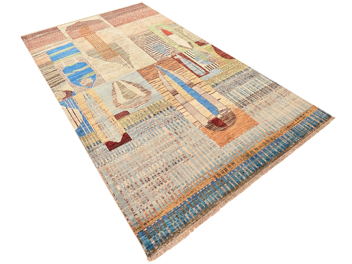 Multicolor geometric area rug with abstract motifs and border fringe, shown from an angle.