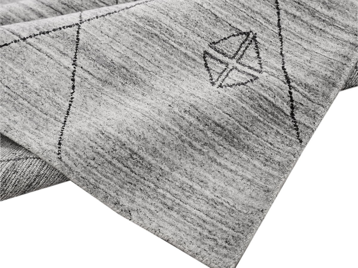 Textured gray rug corner with dark geometric symbols stitched in rows.