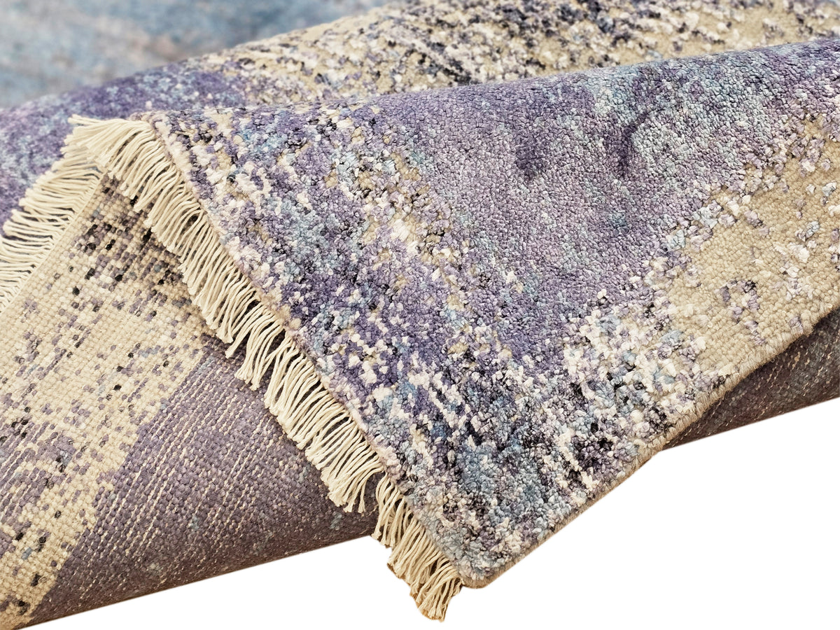 Abstract rug corner with fringed edge and speckled blue, beige, and purple texture