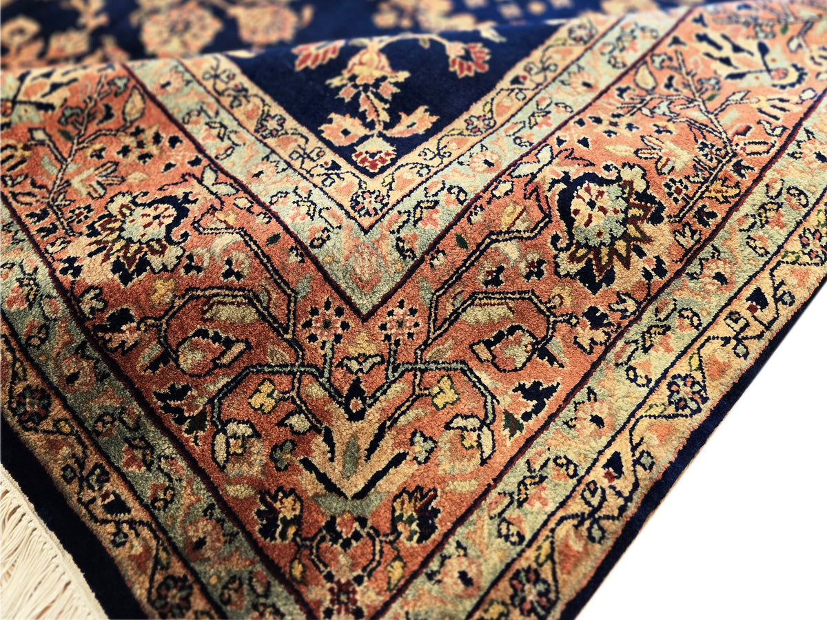 Close-up of navy Sarouk rug with rust vine motifs, cream outlines, intricate pattern