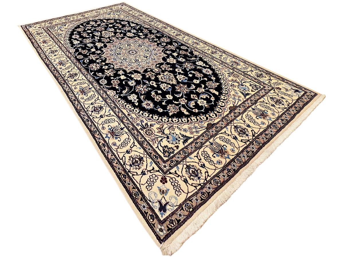 Area rug with black oval medallion, cream border, and corner tassel fringe