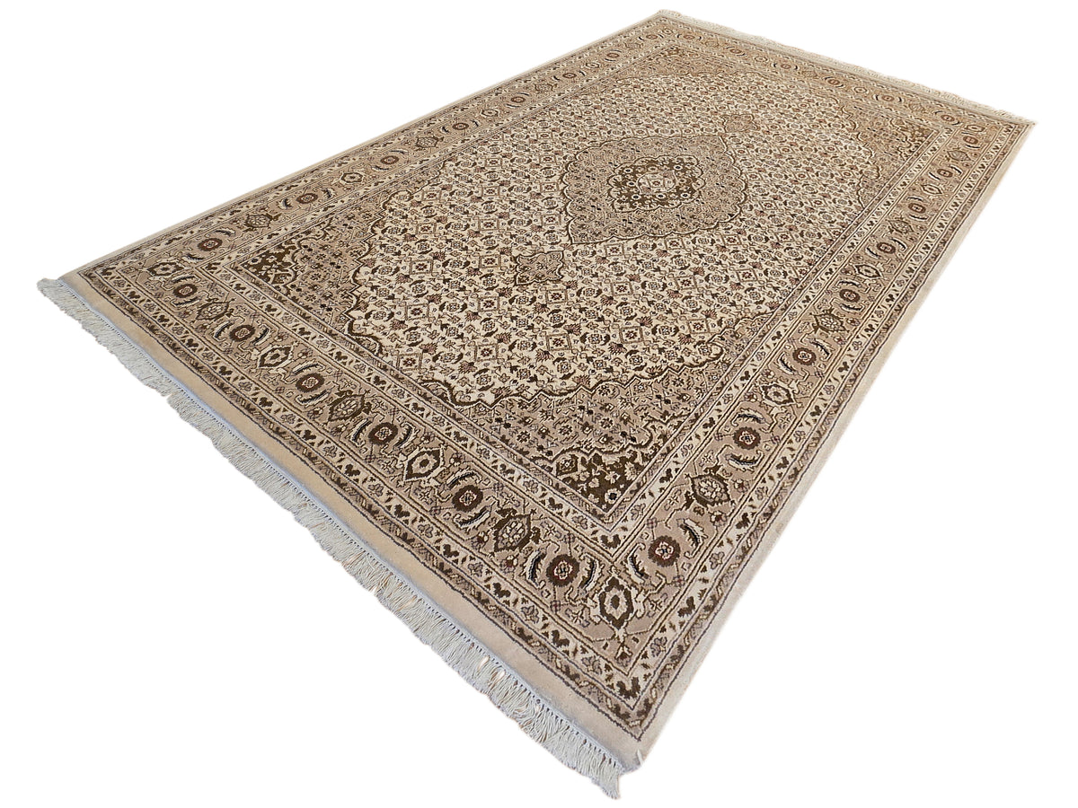 Beige and brown patterned area rug with central medallion, border, and short fringes.