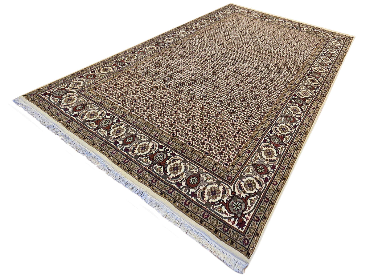 Beige area rug with dark border medallions and blue edge fringe