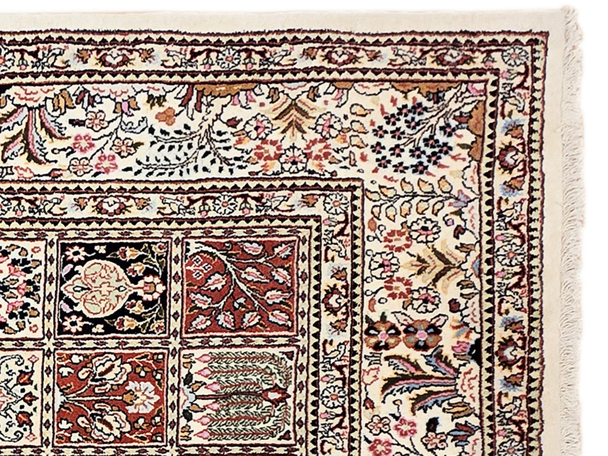 Close-up of multicolor ornate rug border with floral vines and fringed edge.