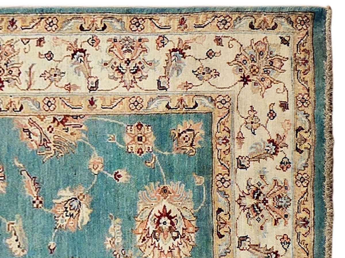 Close-up of turquoise rug with ivory medallions, red details, and intricate border motifs