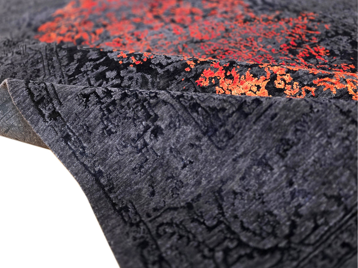 Dark navy rug with orange-red abstract floral pattern, textured surface detail view