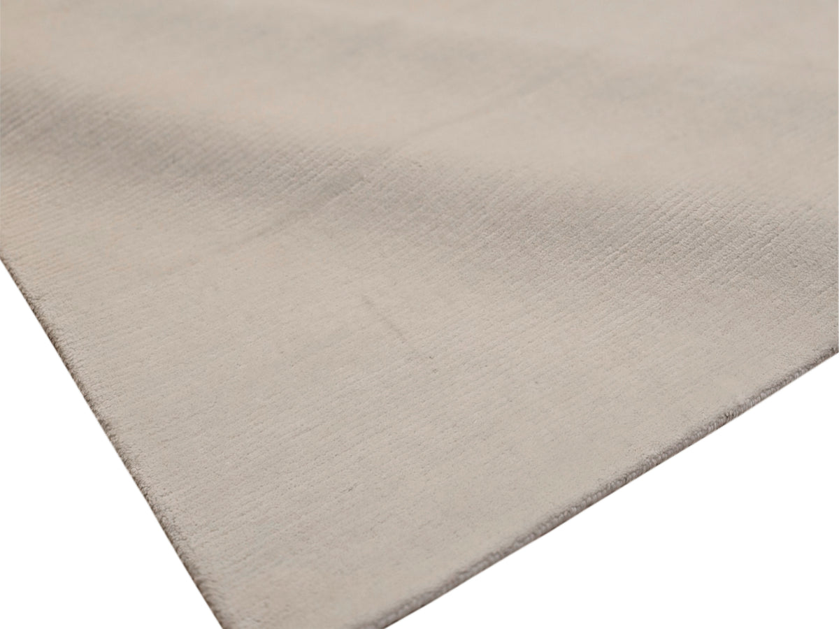 Light beige rug edge and surface close-up with fine woven texture visible.