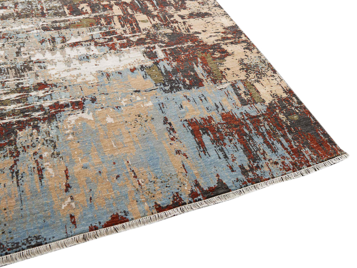 Abstract area rug in beige, pale blue and rust with dark streaks and frayed edge.