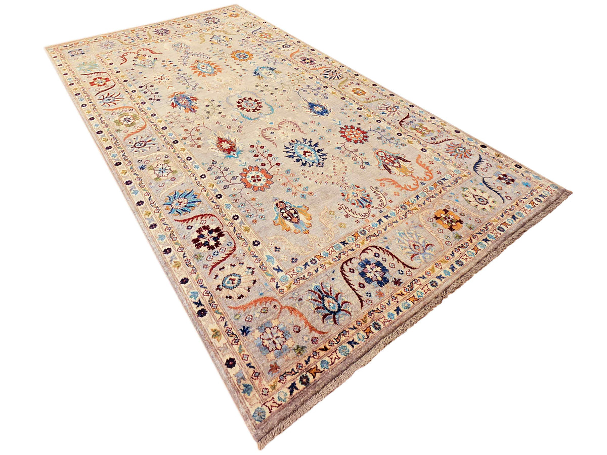 Light beige area rug with multicolor floral motifs, border detailing, and fringed corners