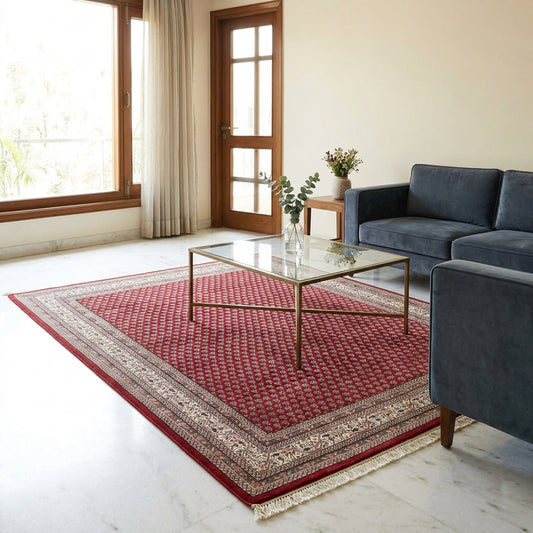 Red area rug with geometric pattern, cream border, and short fringe on floor.