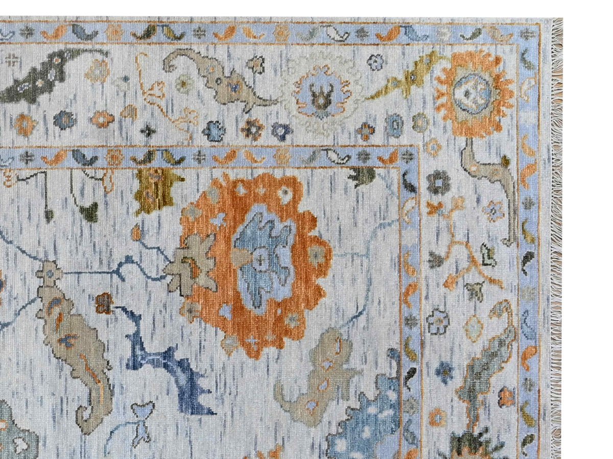Close-up of Oushak-style rug in light blue with orange medallion, floral rosettes and pattern lines