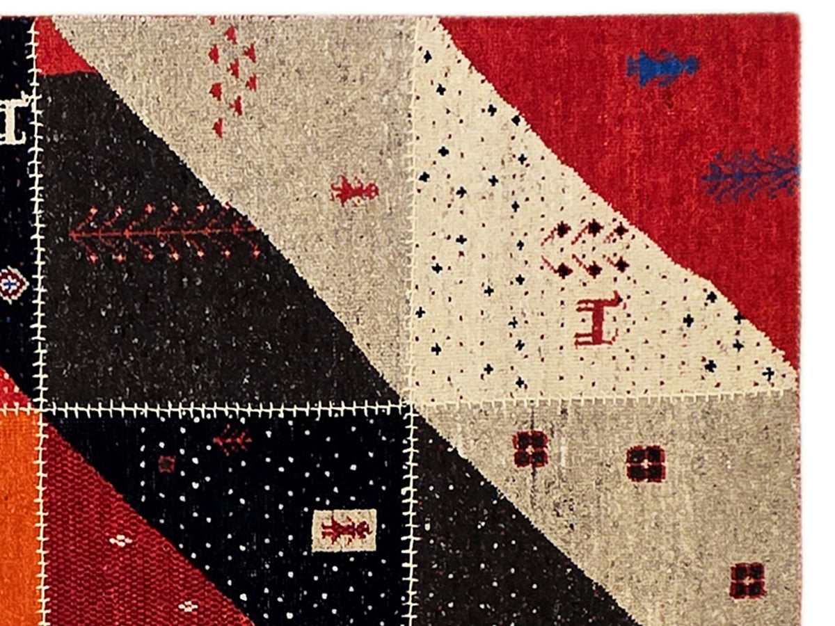 Close-up of patchwork rug: red, black, and cream triangular motifs with speckled texture