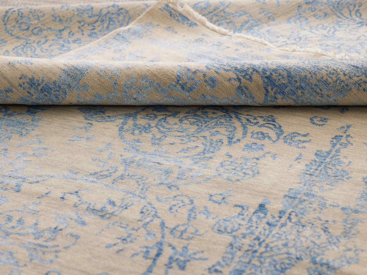 Close-up of blue-and-beige rug texture with ornamental pattern and visible woven surface.