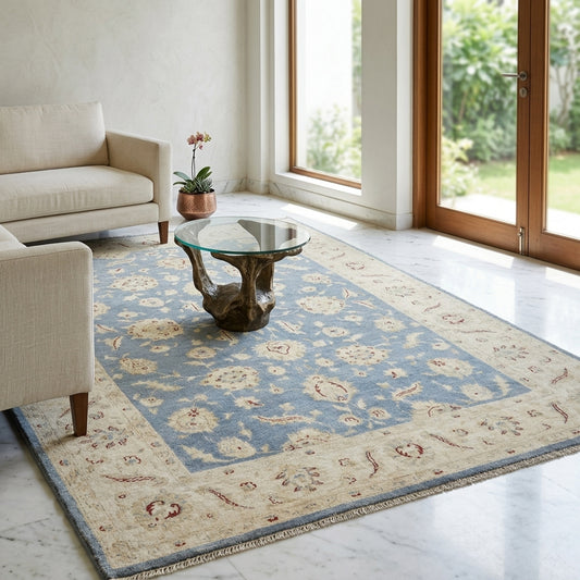 Afghan rug styled on floor with cream border, blue center, and scattered red floral motifs