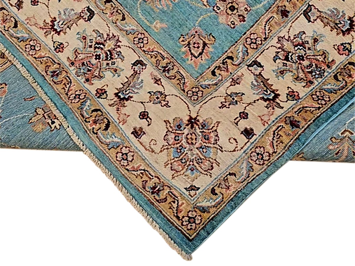 Corner view of turquoise rug with ivory medallion, red accents, and fringed edge